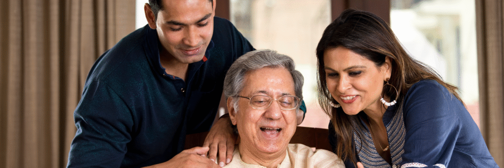 Happy elderly man spending time with his adult son and daughter at home, symbolizing family care, support, and health awareness.